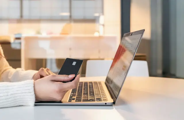 Woman paying with a card at her laptop